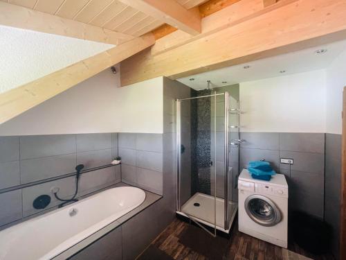 a bathroom with a tub and a washing machine at Ferienwohnung Allgäunest in Argenbühl