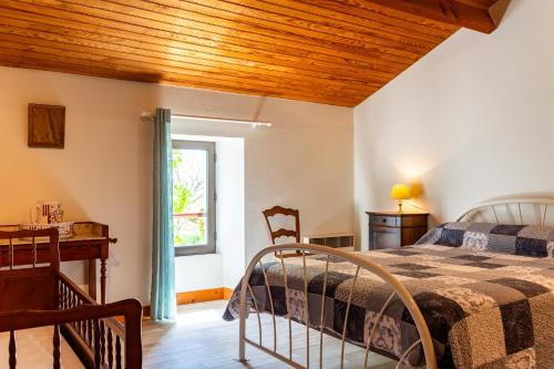 a bedroom with a bed and a desk and a window at La Maison de Piquereau in Sauveterre-de-Guyenne