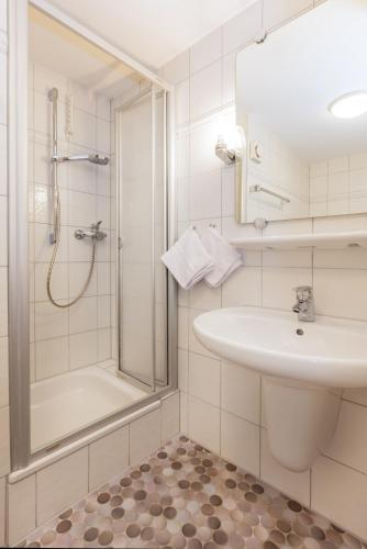 a white bathroom with a sink and a shower at Hotel Liberia in Oberstdorf