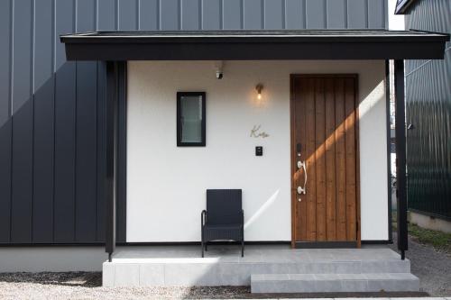 a building with a door and a chair on the steps at Kuro in Hakodate