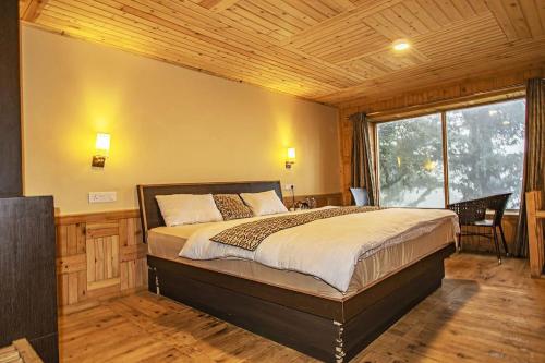 a bedroom with a bed and a large window at Agyaat Vaas in Bāgi