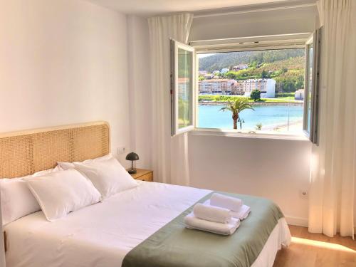 a bedroom with a bed and a window with towels on it at A Ribeira - BoaOnda in Cee