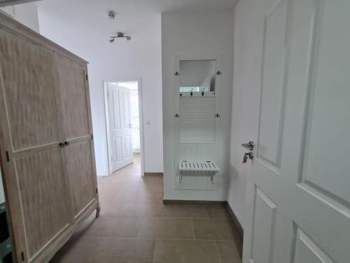 a hallway with a white room with a door and a mirror at Ferienwohnung Inselblick Vitzdorf in Fehmarn