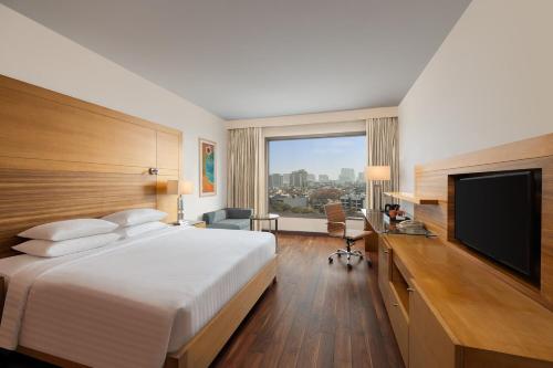 a hotel room with a bed and a flat screen tv at Courtyard by Marriott Gurugram Downtown in Gurgaon