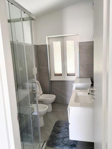 a bathroom with two toilets and a sink and a shower at Fiorucci Apartments - Marco's House in Focene