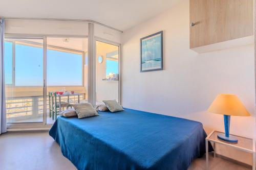 a bedroom with a blue bed with a view of the ocean at Studio vue mer in Canet-en-Roussillon