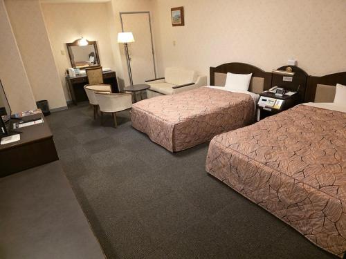 a hotel room with two beds and a table and chairs at Nobeoka Urban Hotel in Nobeoka
