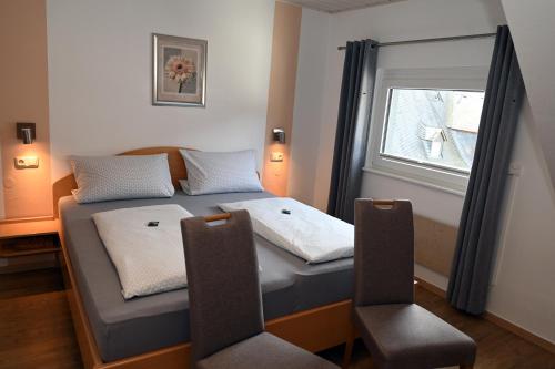two beds in a room with two chairs and a window at Wein- und Gästehaus M. Bai in Mesenich