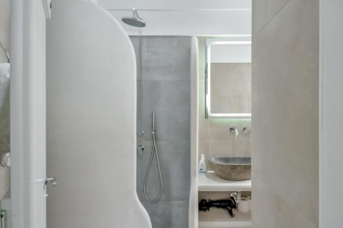 a bathroom with a sink and a shower with a mirror at Politimis Studio N3 in Amorgos