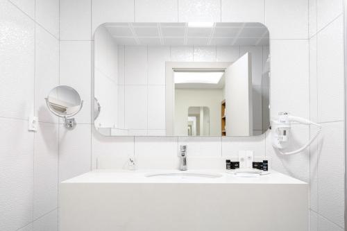 a white bathroom with a sink and a mirror at Avwan Hotels Collection in İzmir
