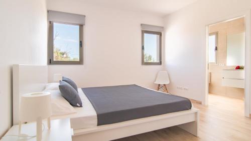 a white bedroom with a bed and two windows at Can Colomer Ferragut in Artá