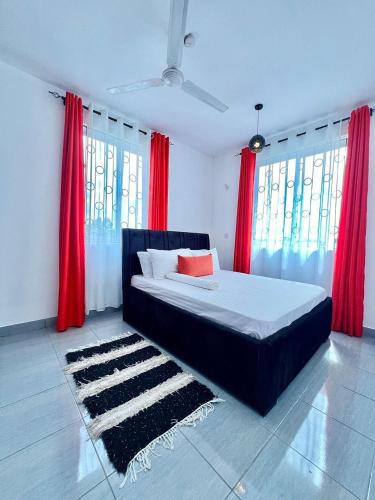 a bedroom with a bed with red curtains and a rug at Auryhomes in Mombasa