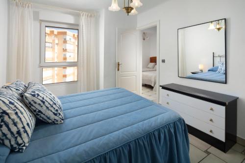 a bedroom with a blue bed with a dresser and a mirror at Bloque 76 in Torrox