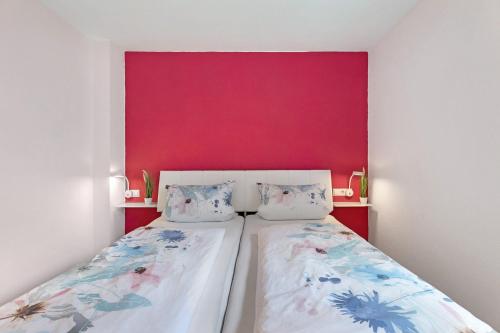a bedroom with two beds and a red wall at Ferienwohnung Bruttel in Gaienhofen