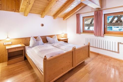a bedroom with a large wooden bed with white sheets at Mansardenwohnung Egart in Resia