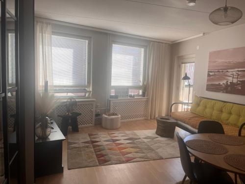a living room with a yellow couch and a table at Great two bedrooms apartment with a private sauna and a sea view from the balcony close Helsinki center in Helsinki