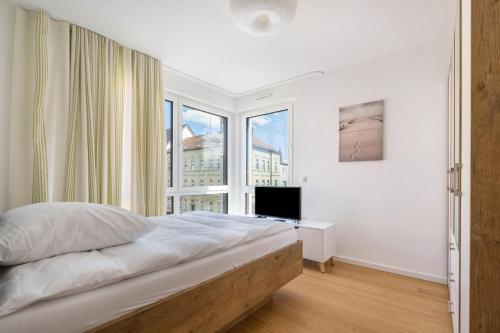 a white bedroom with a bed and a window at Apartment-Ernst in Finsterwalde