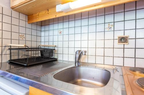 a kitchen with a sink and a tiled wall at Chalet de la Marmotte in Crest-Voland