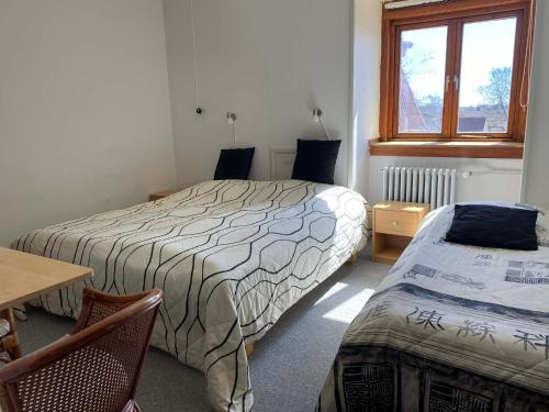 a bedroom with two beds and a table and a window at Pension Elmehøj in Hjertebjerg