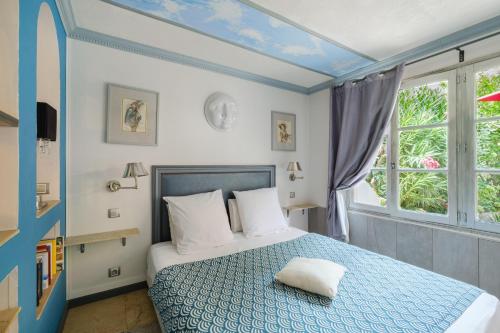 a bedroom with a blue and white bed and a window at Sous L'olivier in Menton
