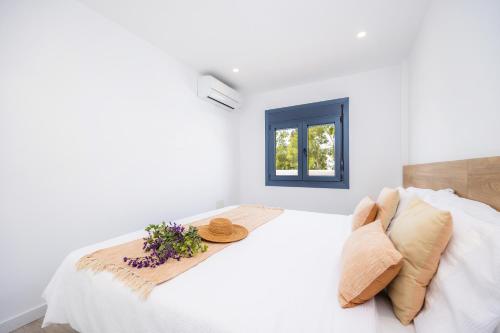 a white bedroom with a bed and a window at White suites 3 in Cala d´Or
