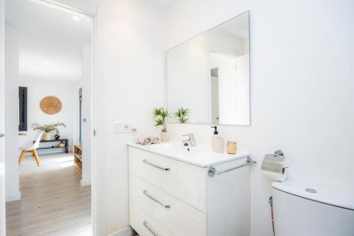 a white bathroom with a sink and a mirror at White suites 3 in Cala d´Or