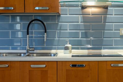 a kitchen with a sink and a blue tiled wall at Thomas' House in Alghero