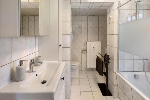 a bathroom with a sink and a toilet and a tub at Ferienwohnung Kleinbreitenbach in Plaue