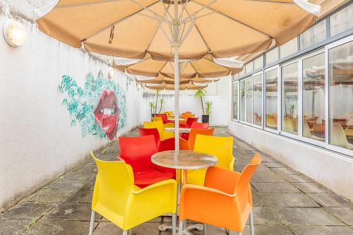 a table with colorful chairs and an umbrella at HI Lisboa - Pousada de Juventude in Lisbon