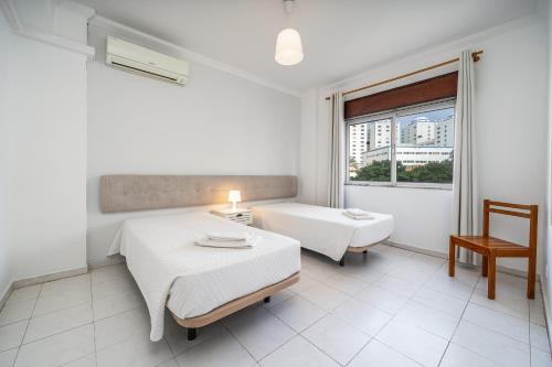 a white room with two beds and a window at Squash Club Portimão in Portimão