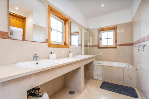 a bathroom with a sink and a tub and a mirror at Villa Alvor in Alvor