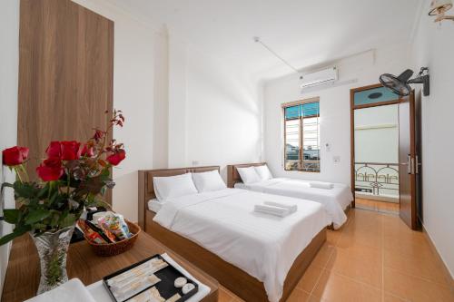 a bedroom with two beds and a vase with red roses at South Star Hotel in Ninh Binh