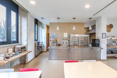 a large kitchen with tables and red chairs at HI Vila Nova de Cerveira - Pousada de Juventude in Vila Nova de Cerveira