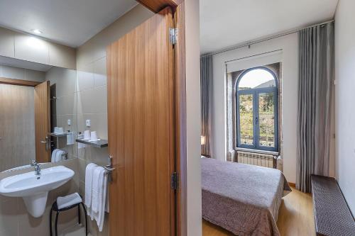 a bathroom with a sink and a bed and a window at HI Vila Nova de Cerveira - Pousada de Juventude in Vila Nova de Cerveira