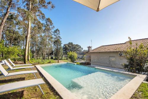 a swimming pool with two chairs and a house at Villa da Floresta in Arcos