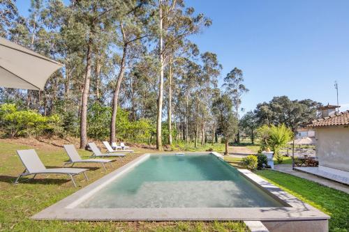a swimming pool in a yard with chairs and an umbrella at Villa da Floresta in Arcos