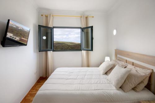 a bedroom with a large white bed and a window at Apartamento Ye in Haría