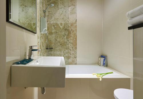 uma casa de banho branca com um lavatório e um chuveiro em Hotel 81 Gold em Singapura