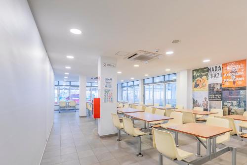 a dining room with tables and chairs and windows at HI Lisboa - Pousada de Juventude in Lisbon