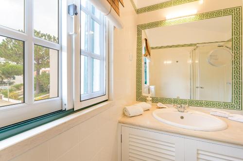 a bathroom with a sink and a mirror and windows at Casa de praia na costa da Galé in Melides