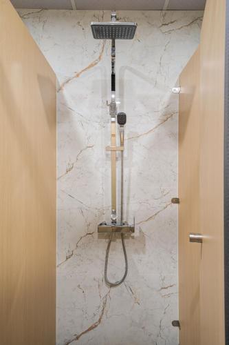 a shower in a bathroom with a white marble wall at 2Re Hidden Hostel 58 Hàng Bạc in Hanoi