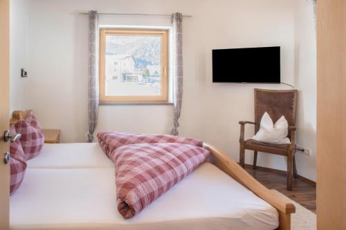 a bedroom with a bed and a tv and a chair at Appartement Julia in Achenkirch