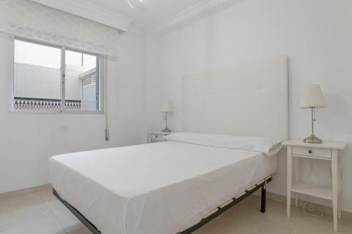 a white bedroom with a large bed and a window at Casa Ricardo in Barbate