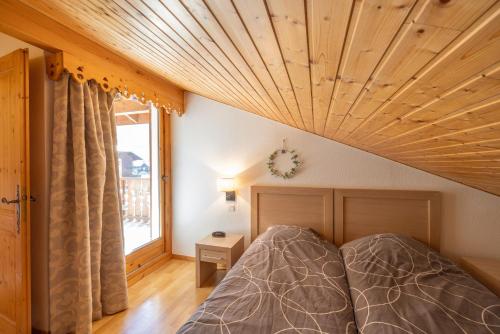 a bedroom with a bed and a wooden ceiling at Appt le grand Tetras D20 in Samoëns