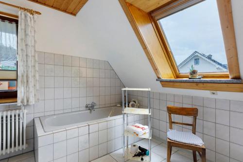 a bathroom with a tub and a chair and a window at Ferienwohnung Haus Barbara in Bräunlingen