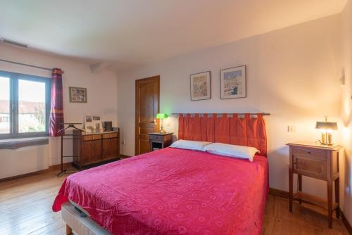 a bedroom with a bed with a red bedspread at Maison avec piscine in Marciac
