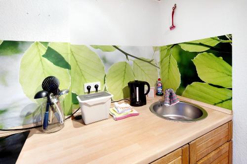 a bathroom counter with a sink and green leaves on the wall at Vogelsberger Bett 5 die 2 in Alsfeld