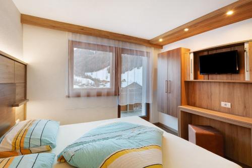 a bedroom with a bed and a flat screen tv at Pension Waldheim Apartments in San Giacomo