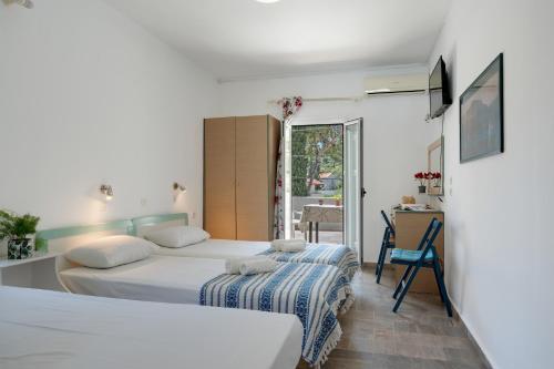 a bedroom with two beds and a desk and a window at Ilias Studios Sevasti Kalymnos in Panormos Kalymnos