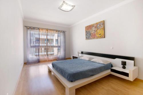 a white bedroom with a bed and a window at Apartamento Armação de Pêra in Armação de Pêra